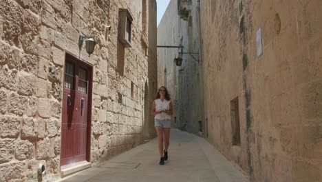 Turista-Solitaria-Caminando-En-La-Calle-Angosta-De-Mdina,-Malta