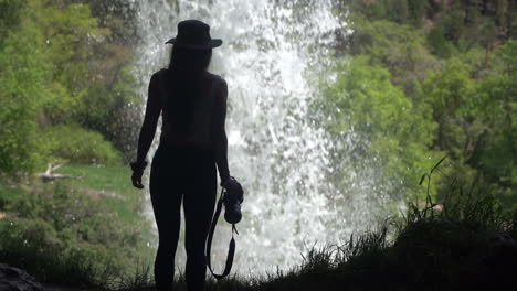Silhouette-Einer-Frau,-Die-In-Einer-Höhle-Unter-Einem-Wasserfall-Spazieren-Geht