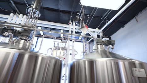 Stainless-stills-in-brewery,-beer-manufacturing-equipment-in-warehouse,-4K