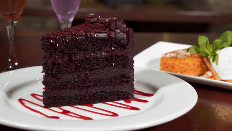 Ein-Dekadentes-Stück-Vierschichtiger-Schokoladenkuchen-Mit-Beerennieselregen,-Feine-Dessertauswahl-Auf-Dem-Esstisch,-Schieberegler-Nahaufnahme-Hd