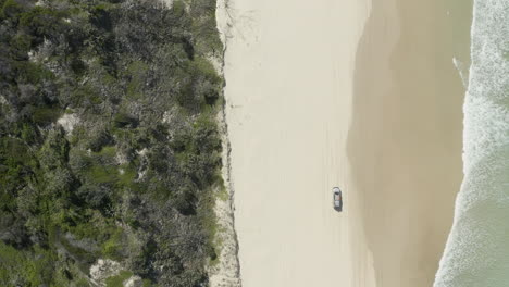 4k-drone-shot-of-a-car-driving-on-a-white-beach