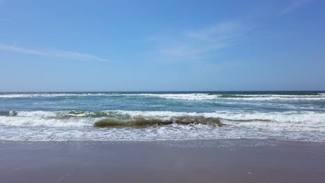 Blue-ocean-waves-on-the-sandy-beach-and-clear-blue-sky