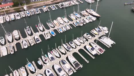 California-Ventura-Harbor-full-of-many-sailboat-yachts-moored-to-pier,-aerial-view