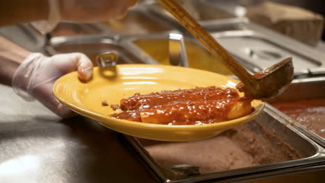 Cook-ladles-red-chile-con-carne-sauce-over-enchiladas,-slow-motion-HD