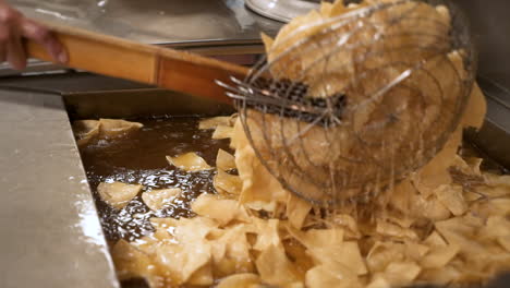 Fry-cook-flips-corn-tortilla-chips-with-spider-strainer-in-restaurant-kitchen,-slow-motion-HD