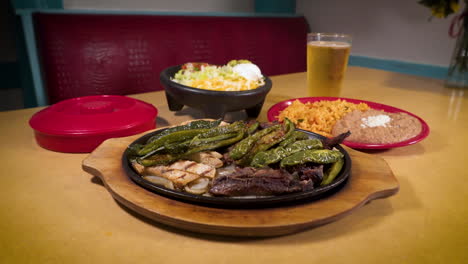 Beef-and-chicken-fajitas-with-peppers-and-onions,-refried-beans,-mexican-rice,-beer,-slider-HD