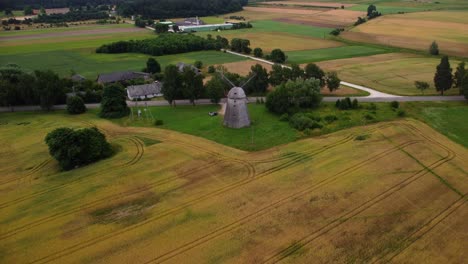 aerial-shot-of-an-old-windmill-in-the-field-by-the-road,-zoom-out
