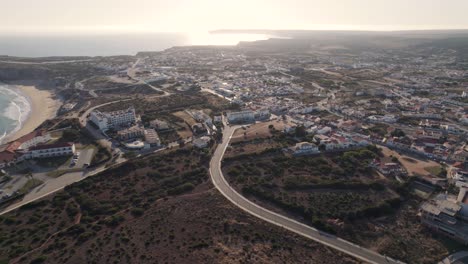 Luftaufnahme-Von-Sagres-Stadtbild-Bei-Sonnenuntergang-Und-Sagres-Point-Landspitze,-Algarve,-Portugal
