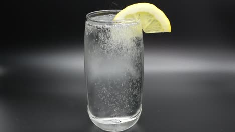 Verter-Agua-Mineral-En-Un-Vaso-Con-Una-Rodaja-De-Limón