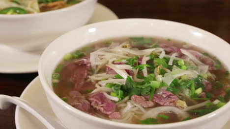 Two-large-bowls-of-Asian-noodle-soups,-huge-servings-of-vietnamese-pho,-slider-close-up-4K