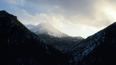 Statische-Luftdrohnenaufnahme-Einer-Winterlandschaft-Des-Mount-Timpanogos-Im-Hintergrund,-Umgeben-Von-Einem-Pinienwald-Während-Des-Sonnenuntergangs-Aus-Dem-Gefrorenen-Tibble-Fork-Reservoir-Im-American-Fork-Canyon,-Utah