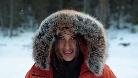 A-beautiful-Brazilian-woman-in-a-large-winter-coat-laughing-and-smiling-at-the-camera-as-wind-and-snow-passes-by-as-she-stands-on-a-frozen-lake-on-a-cold-winter-day-in-American-Fork-Canyon,-Utah