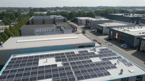 Low-aerial-over-photovoltaic-solar-panel-on-office-rooftop-on-industrial-terrain