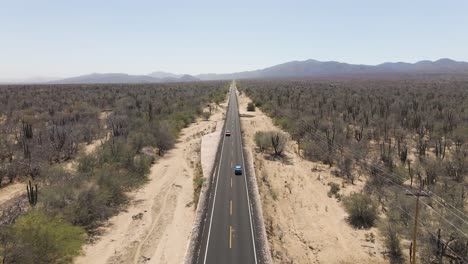 Aerial:-car-driving-on-straight-road-through-desert,-long-car-journey