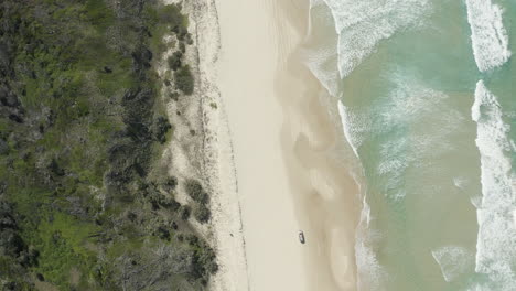4k-aerial-shot-following-a-car-driving-along-the-beautiful-beach-on-Fraser-Island,-Australia