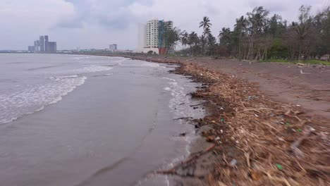 Polluted-contaminated-garbage-aerial-beach-shore-coastline-forward-cloudy-day