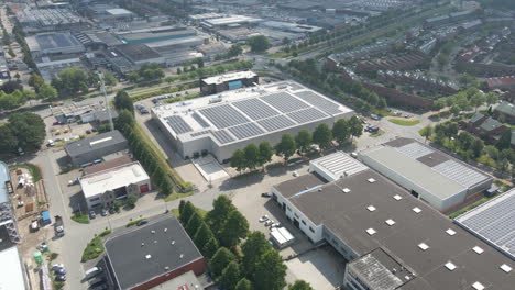 Cinematic-aerial---flying-towards-large-industrial-building-with-many-photovoltaic-solar-panels-on-rooftop