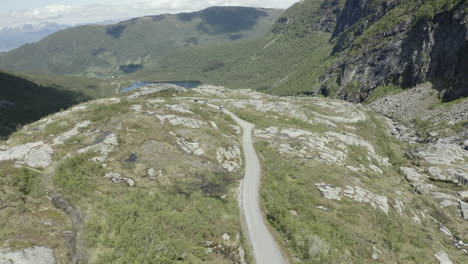 Drone-shot-of-three-car-vans-driving-on-a-small-road-in-Norway