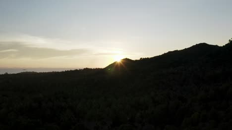 Bright-sunshine-emerges-from-edge-of-mountain-on-Koh-Phangan,-sunset