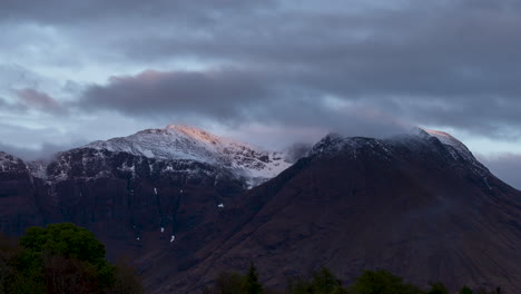 Schottische-Highlands-Zeitraffer,-Schneebedeckte-Berge-über-Invercoe,-Glencoe,-Schottland,-Mit-Abendsonne,-Die-Die-Spitzen-Der-Berge-Und-Nebel-Auf-Dem-Gipfel-Sprenkelt