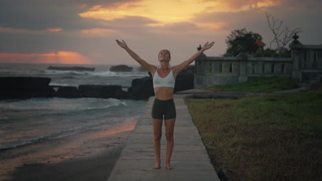 Woman-practicing-sun-salutation-asana-yoga-pose-outside-during-moody-sunset