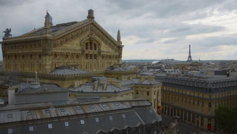 Rear-Exterior-Of-Opera-Garnier-As-Viewed-From-Galeries-Lafayette-In-Paris,-France-With-Eiffel-Tower-In-Far-Distance
