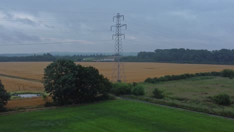 Electricity-steel-pylon-high-voltage-wires-in-countryside-agricultural-farm-field-aerial-view-early-morning-low-angle-slow-right-orbit