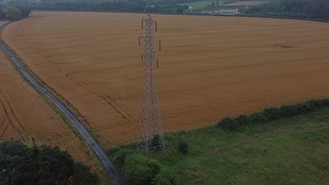 Electricity-steel-pylon-high-voltage-wires-in-countryside-agricultural-farm-field-aerial-view-early-morning-orbit-right