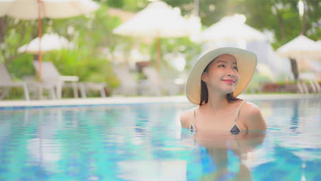 Dreamy-scene-with-beautiful-happy-asian-woman-in-swimming-pool-with-floppy-hat,-full-frame-slow-motion