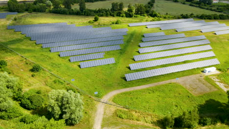 Luftrückwärtsflug-über-Sonnenkollektoren---Nachhaltigkeit-Und-Erneuerbare-Energie-Umgeben-Von-Grüner-Landschaft-Bei-Sonnenlicht