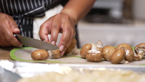 Hands-seen-chopping-off-mushroom-stems-with-a-sharp-chef's-knife---slow-motion