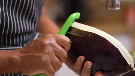 Black,-African-American-hands-seen-peeling-half-of-a-large,-raw-eggplant---isolated-slow-motion
