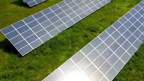 Aéreo,-Reflejo-Del-Sol-En-Paneles-Solares-Ubicados-En-Un-Campo-Verde-En-Gdansk,-Polonia---Planta-De-Energía-Solar