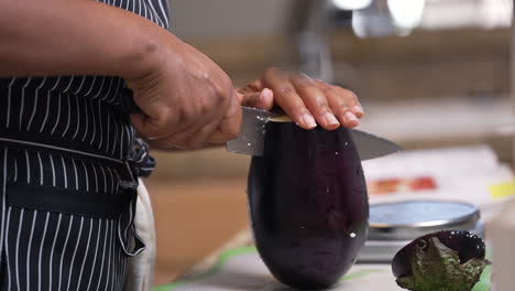 Black,-African-American-hands-slicing-a-large,-whole-eggplant-in-half---isolated-slow-motion