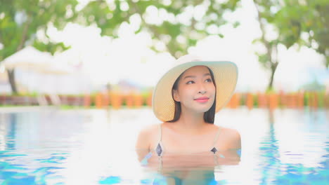 Beautiful-exotic-woman-in-swimming-pool-with-floppy-hat,-close-up,-slow-motion
