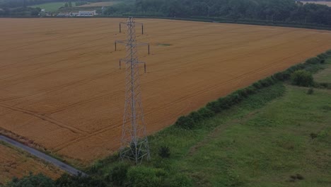 Electricity-steel-pylon-high-voltage-wires-in-countryside-agricultural-farm-field-aerial-view-early-morning-right-orbit-slow