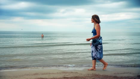 Mature-Woman-Walking-On-The-Beach-Looking-At-The-Sea-In-Karkle-Lithuania---wide-shot