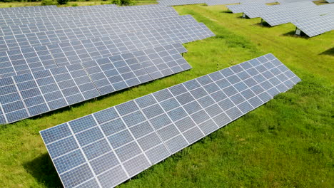 Solar-panel-closeup,-reflection-of-clouds-and-sun-flares-in-the-solar-panel,-aerial-shot-by-drone,-renewable-energy,-solar-panels-on-green-grass-in-Poland