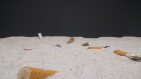 Super-close-up-camera-shot-of-cigarette-butts-lefted-in-the-beach