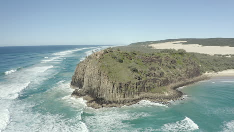4k-drone-shot-of-a-mountain-cliff-next-beautiful-beach-on-a-clear-sunny-day-on-Fraser-Island,-Australia