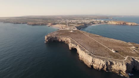 Aerial-pullback-tilt-up-high-cliffs-promontory-Sagres-point-with-Lighthouse-and-Fortress