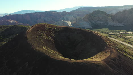 Vista-Aérea-De-Una-Persona-Solitaria-Caminando-Sobre-Un-Cono-De-Ceniza,-Cráter-De-Volcán-Inactivo-En-El-Parque-Estatal-Snow-Canyon,-Utah-Usa