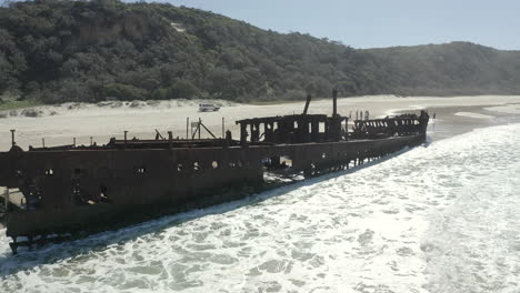 Drone-slowly-orbiting-the-abandoned-SS-Maheno-shipwreck,-washed-up-on-the-coastline-of-Fraser-Island-in-Australia