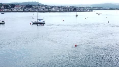Aerial-view-small-motorboat-travelling-Seaside-town-river-Conwy-harbour-marina-tracking-left