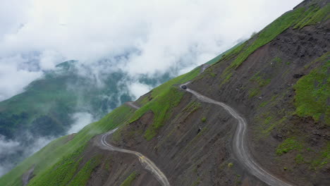 Wide-cinematic-drone-shot-of-vehicle-driving-on-the-edge-of-the-Abano-Pass-in-Tusheti-Georgia,-one-of-the-world's-most-dangerous-roads