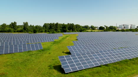 Langsame-Luftpfanne-Mit-Gigantischer-Solarpanel-Farm-In-Ländlichem-Waldgebiet-Mit-Industrieunternehmen-Im-Hintergrund