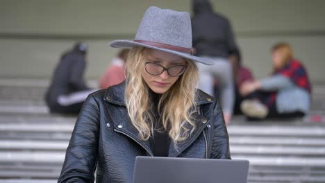 Young-beautiful,-blond-hair-woman-working-outside-with-her-laptop