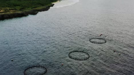 Aerial-dolly-in-pan-down-shot-of-sea-fish-farm,-the-offshore-aquaculture-and-underwater-cage-at-Lambai-island,-Xiaoliuqiu,-Pingtung-county-Taiwan,-Asia