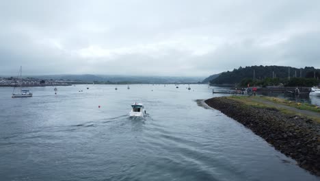 Motorboot-Antenne-Folgen-Hinter-Ansicht-Kommt-Conwy-Küstenstadt-Hafenmündung,-Um-Ruhigen-Fluss-Zu-Navigieren