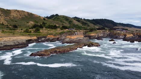 4k-30fps-Luftaufnahmen-Von-Der-Küste-Von-Oregon---Verfolgen-Sie-Einen-Bemoosten-Küstenfelsen,-Während-Die-Meereswellen-Gegen-Felsformationen-Am-Meer-Prallen-Und-Möwenvögel-An-Pnw-Wäldern-Und-Epischem-Gehöfthintergrund-Vorbeifliegen